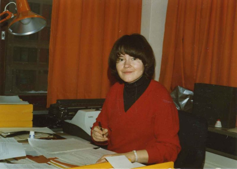 Liisa Kauppinen, the Secretary of the organization for the deaf in Helsinki, seated by a desk.